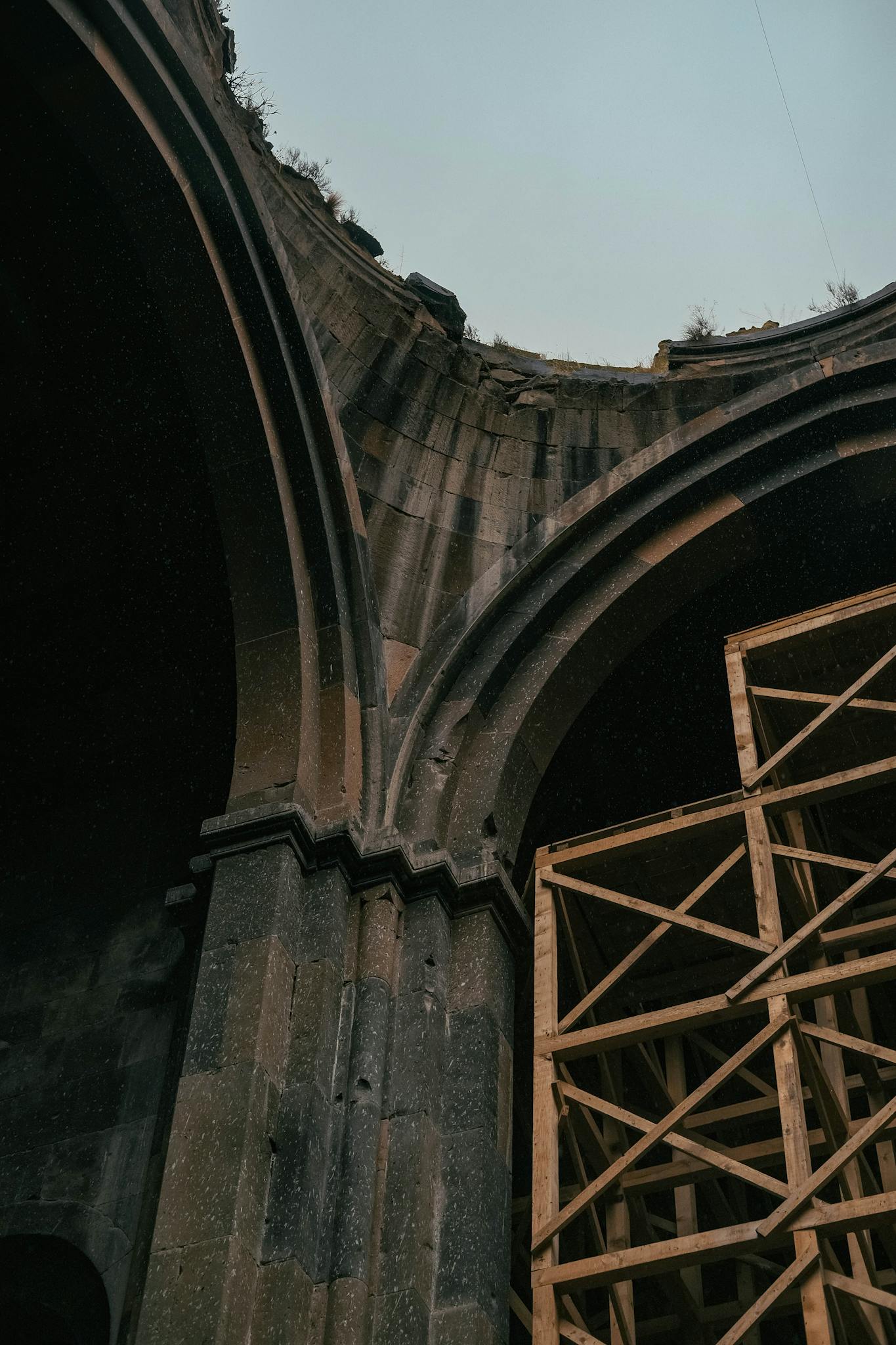 Low-angle view of ancient stone arches with wooden scaffolding under restoration.
